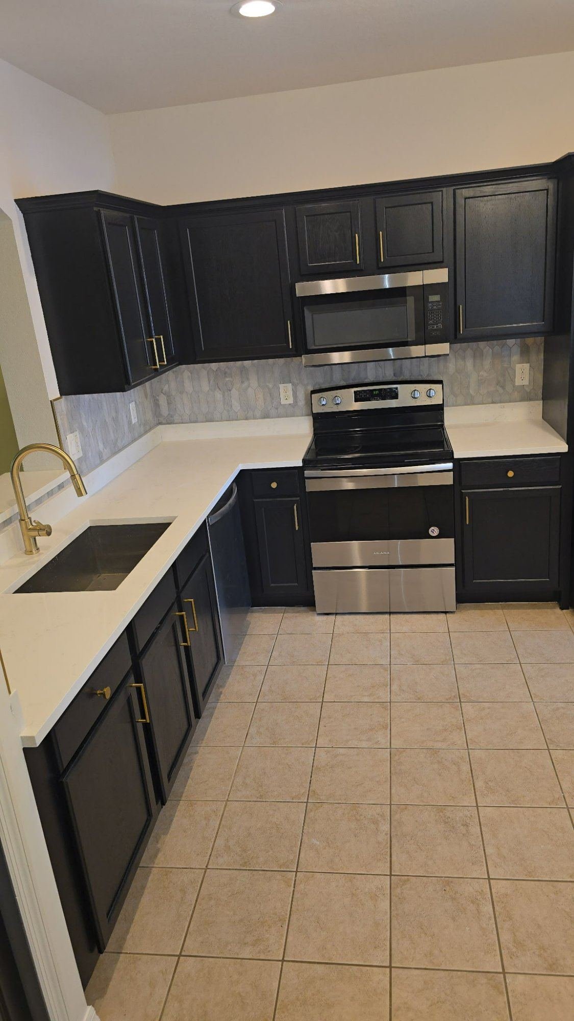 Completed black cabinet kitchen remodel with quartz countertops and gold hardware Cape Coral FL