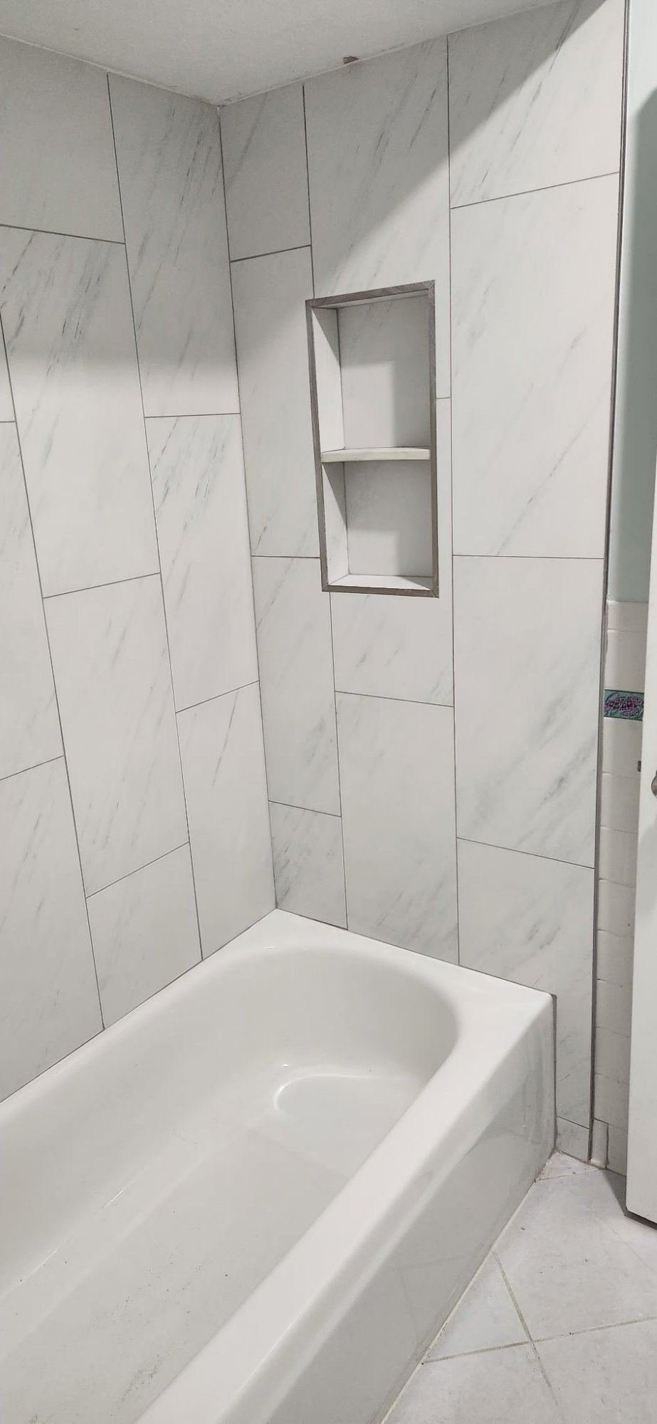 Completed guest bathroom with marble tile tub surround and built-in niche Southwest Florida